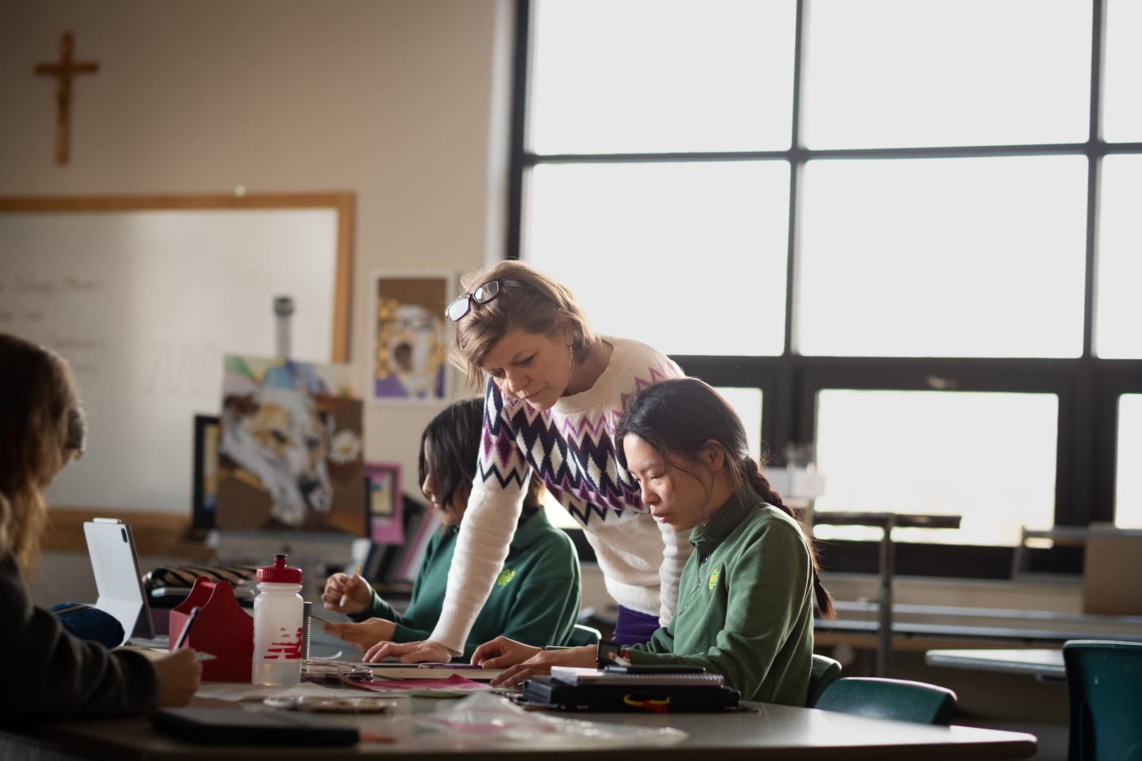 A woman helping a student at a table.