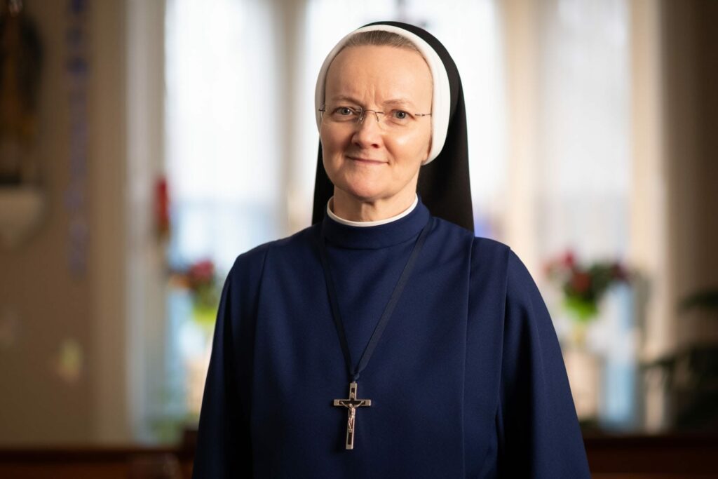A nun with glasses smiling.