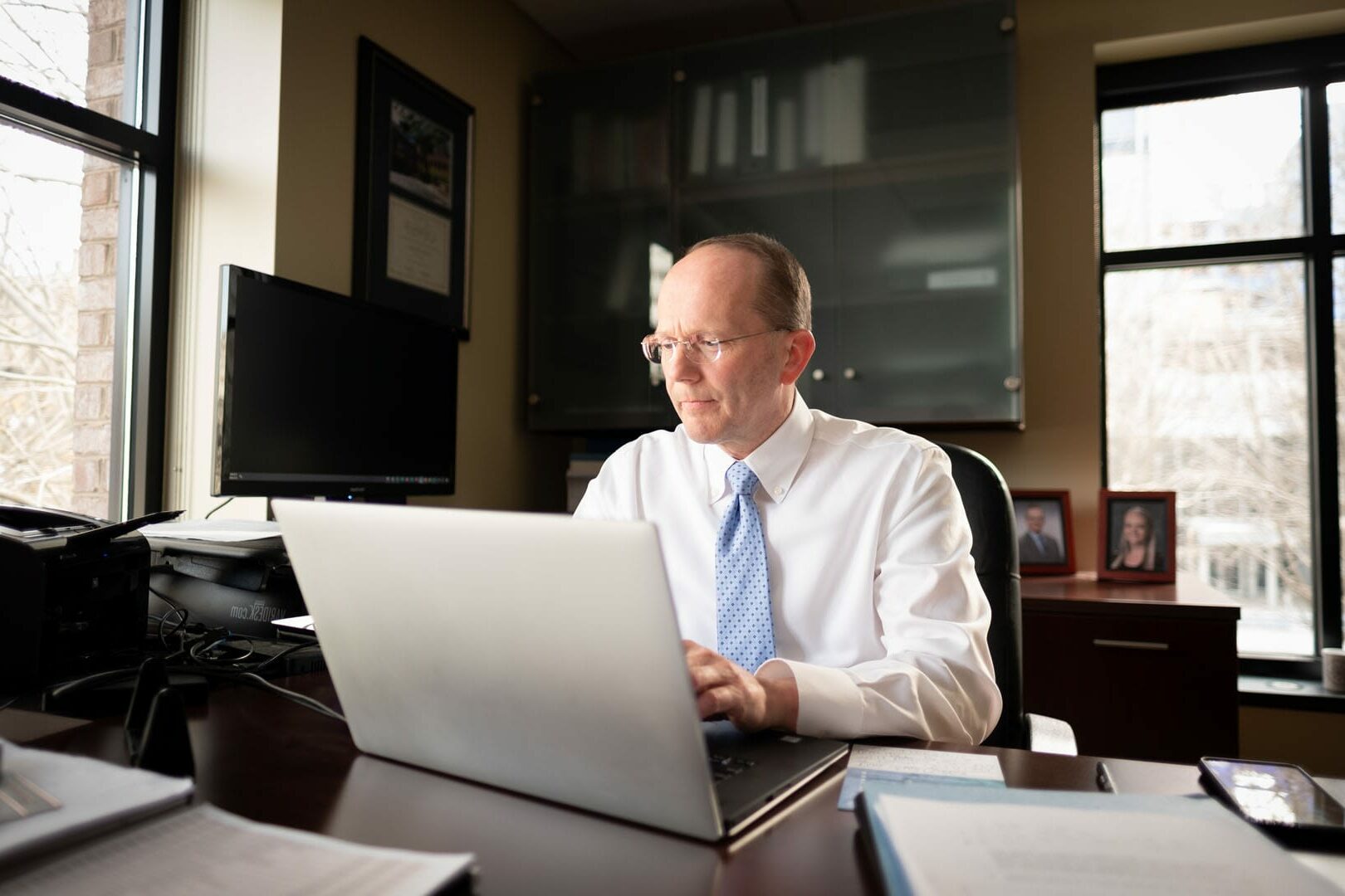 Older man working at a desk on a computer.