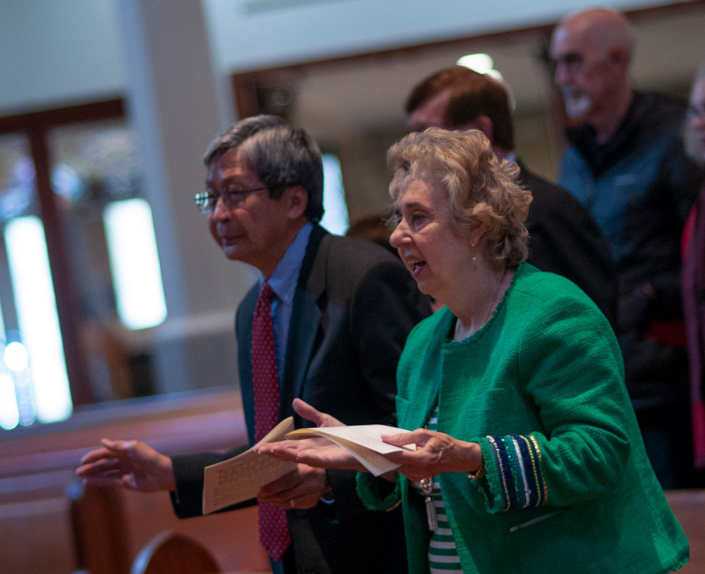 Elderly man and woman standing and singing inside a church.