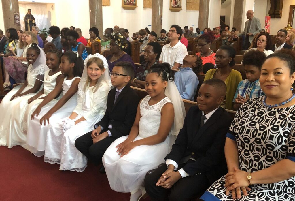 Women and children sitting in the front row of a church smiling.
