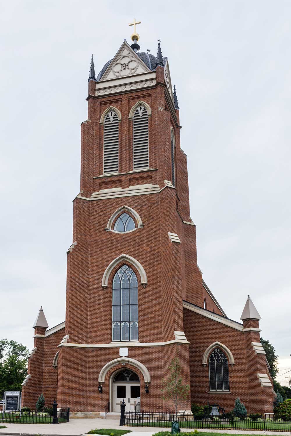Exterior shot of a tall church with shutters and stained glass windows.