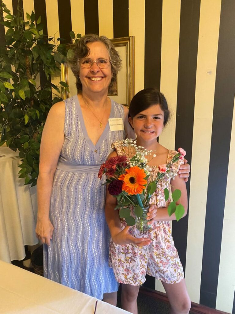 Woman posting with young lady holding flowers.